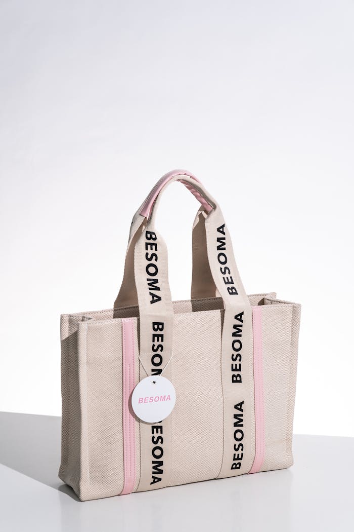 Elegant beige handbag with pink accents, perfect for fashion and shopping enthusiasts.