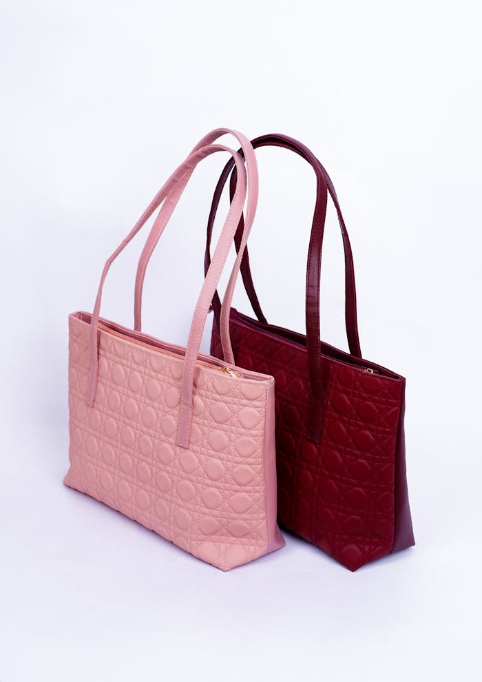 Styled handbags in pink and red displayed in a studio setting on white background.